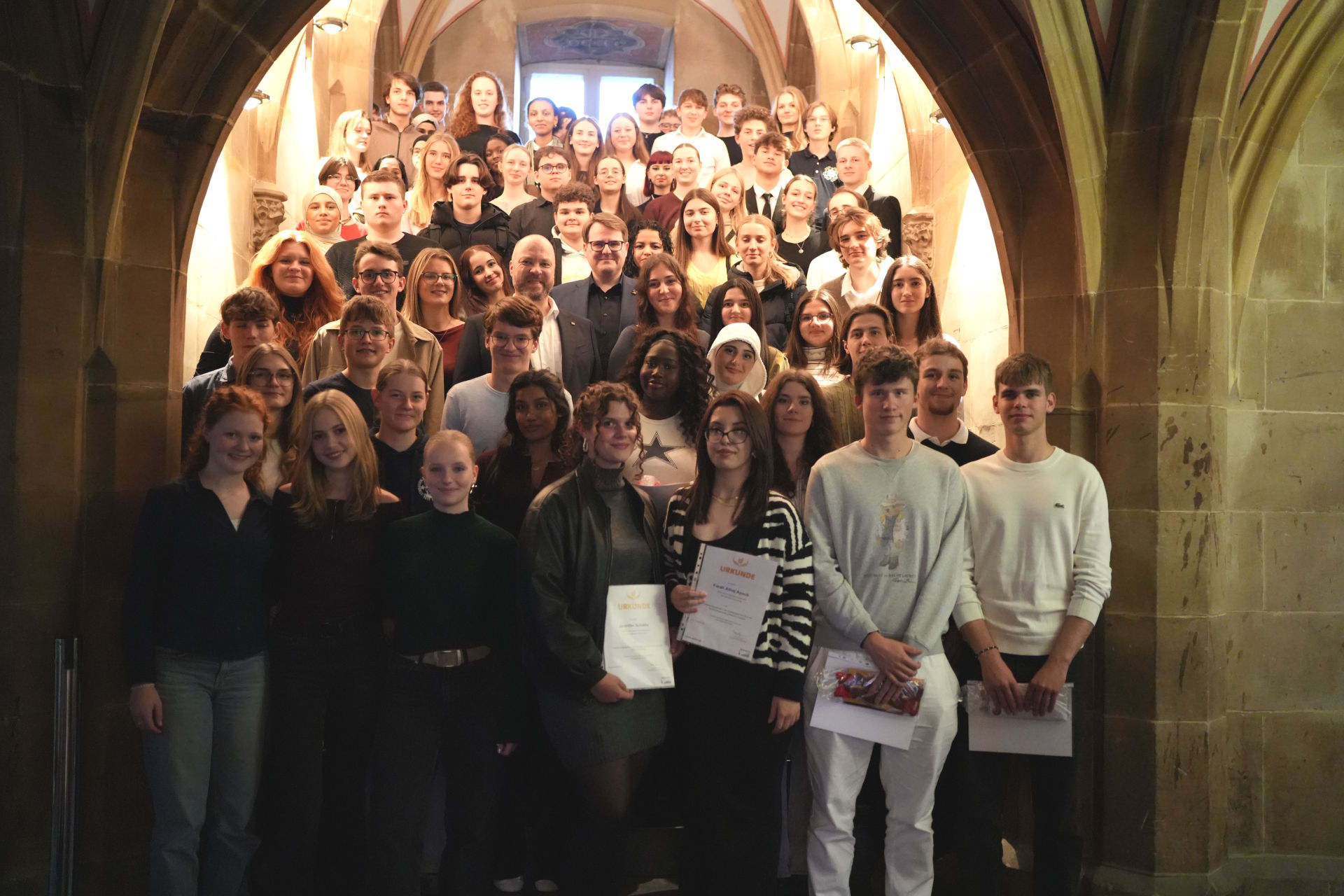 Eine Gruppe Jugendlicher stehend auf einer Mitte im Aachener Rathaus, in der Mitte steht Oberbürgermeister Dr. Michael Ziemons.