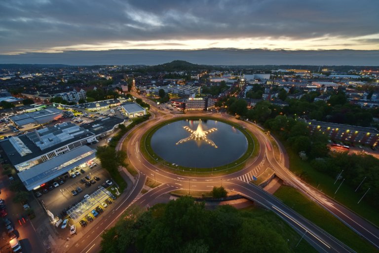 Der große Brunnen auf dem Europaplatz ist aus der Vogelperspektive zu sehen. Es herrscht Sonnenuntergangsstimmung