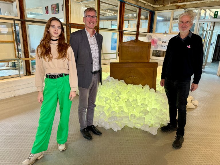 Drei Menschen vor einer Kunstinstallation