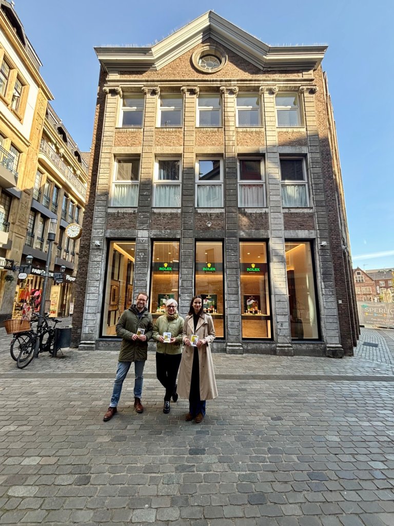 Drei Menschen vor einer alten Hausfassade in der Aachener Innenstadt.