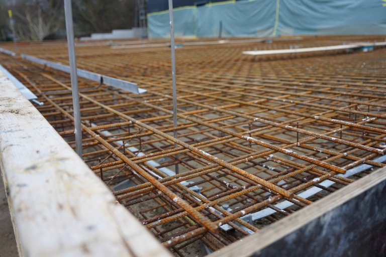 Das Fundament eines Rohbaus ist zu sehen. Stahlgitter ragen aus der Konstruktion.