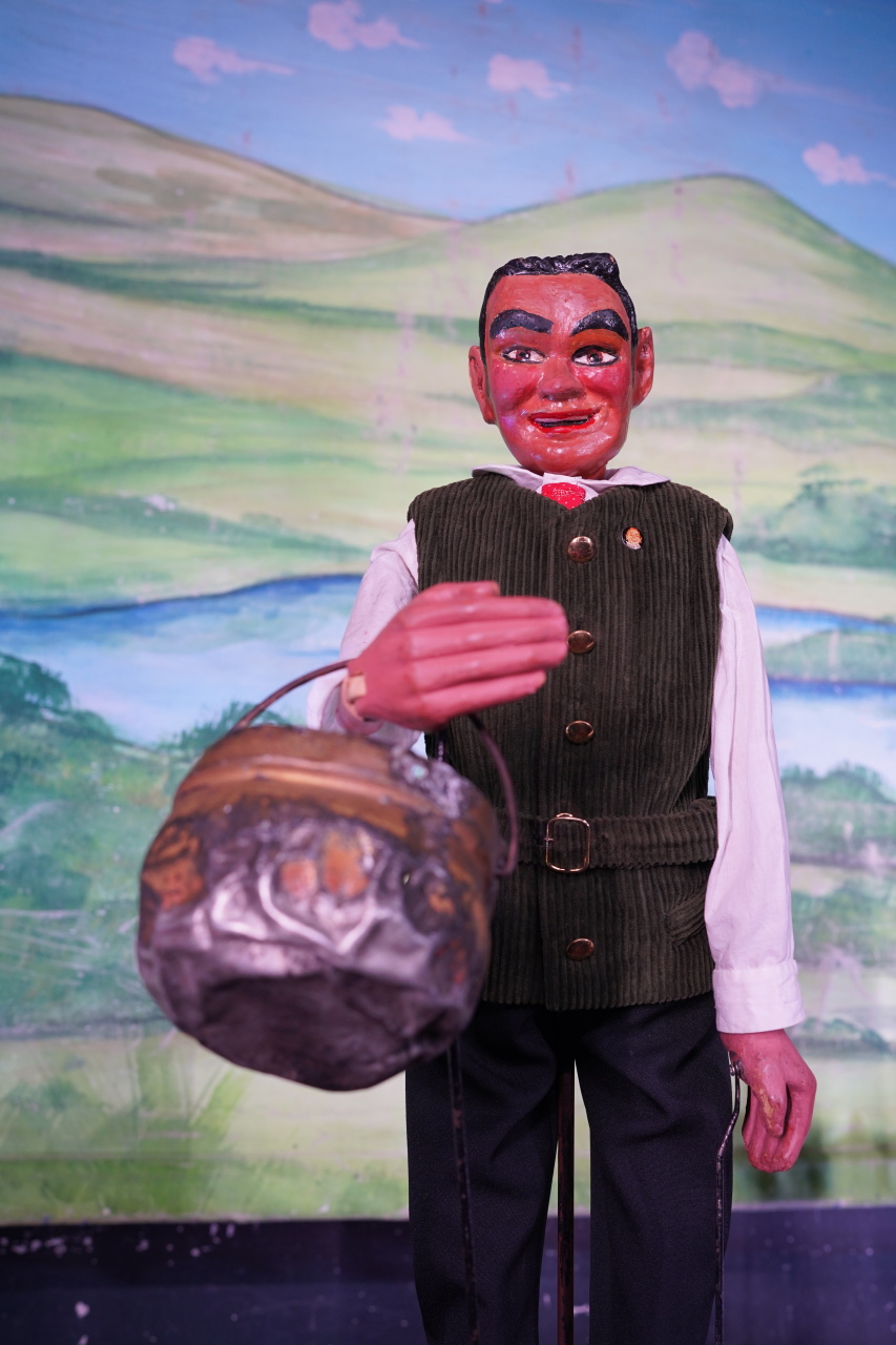 Eine Stabpuppe hält eine Kessel.