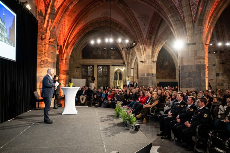 Der Oberbürgermeister steht auf einer Bühne vor Publikum im Krönungssaal.