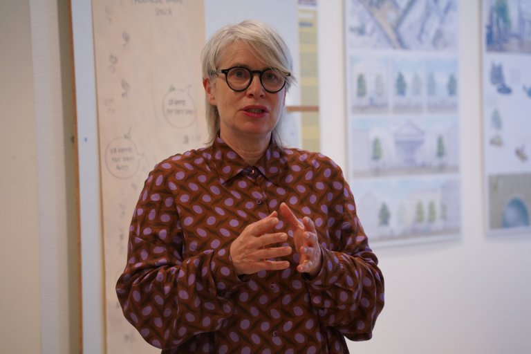 Eine Frau steht in einem Raum und erklärt etwas