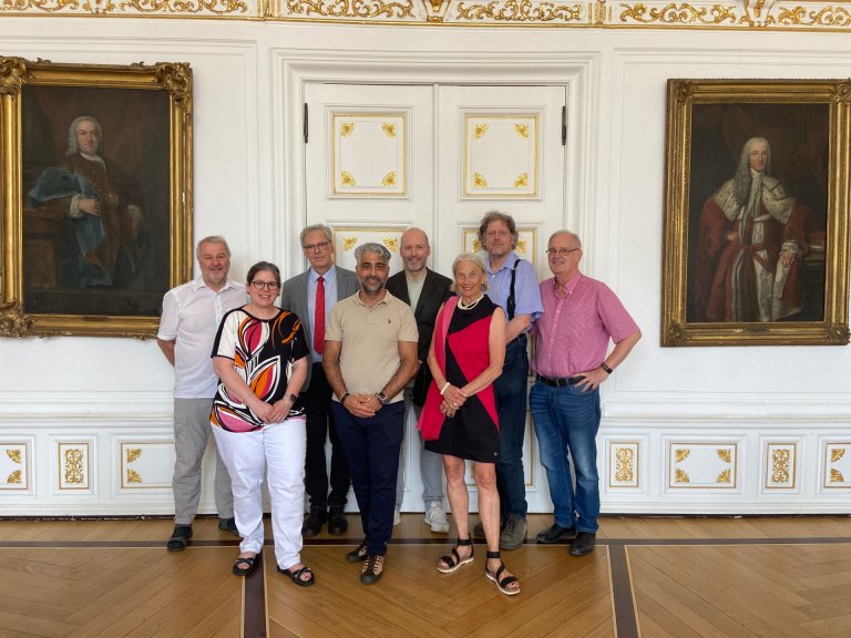 Eine Gruppe von Menschen steht im Weißen Saal im Aachener Rathaus.