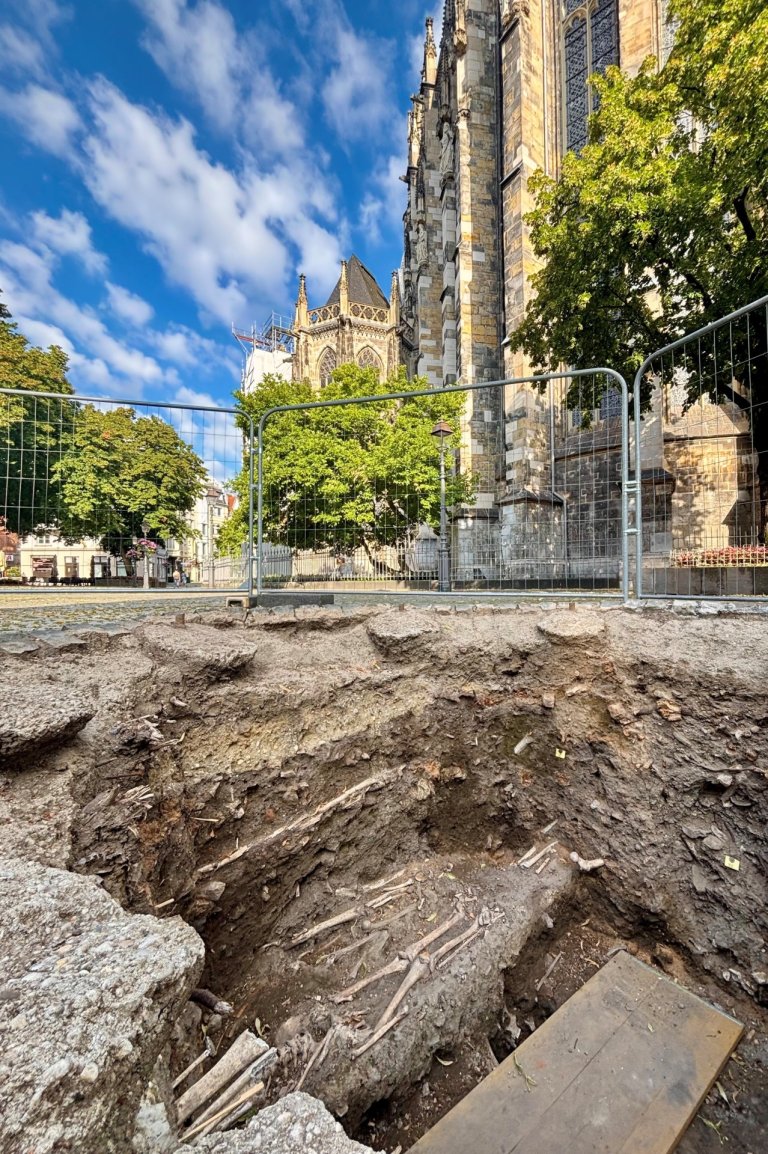 Eine Grube mit einem frei geleten Skelett am Rande des Aachener Doms.