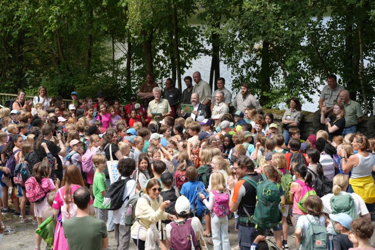 Viele Kinder stehen auf dem Waldspielplatz. Oberbürgermeister Ziemons verkündet die Ergebnisse der Waldjugendspiele.