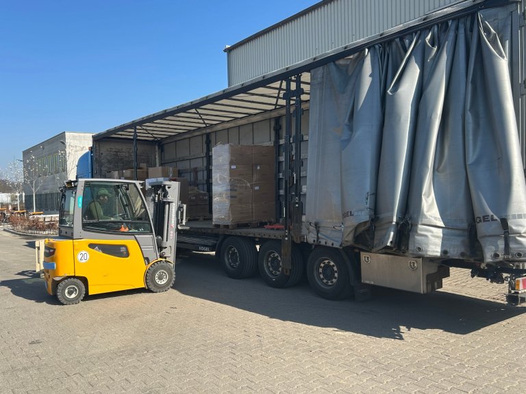 Ein Gabelstapler lädt Hilfsgüter in einen LKW.