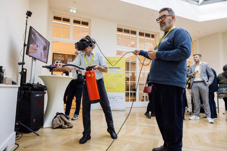 Ein Mensch mit VR-Brille hält einen Feuerlöscher
